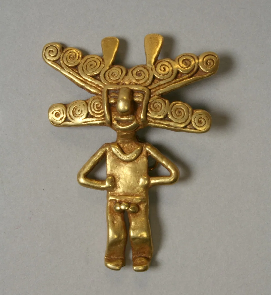 Colgante precolombino de oro con tocado de espirales, atribuido a la cultura quimbaya. Colección del Metropolitan Museum of Art.