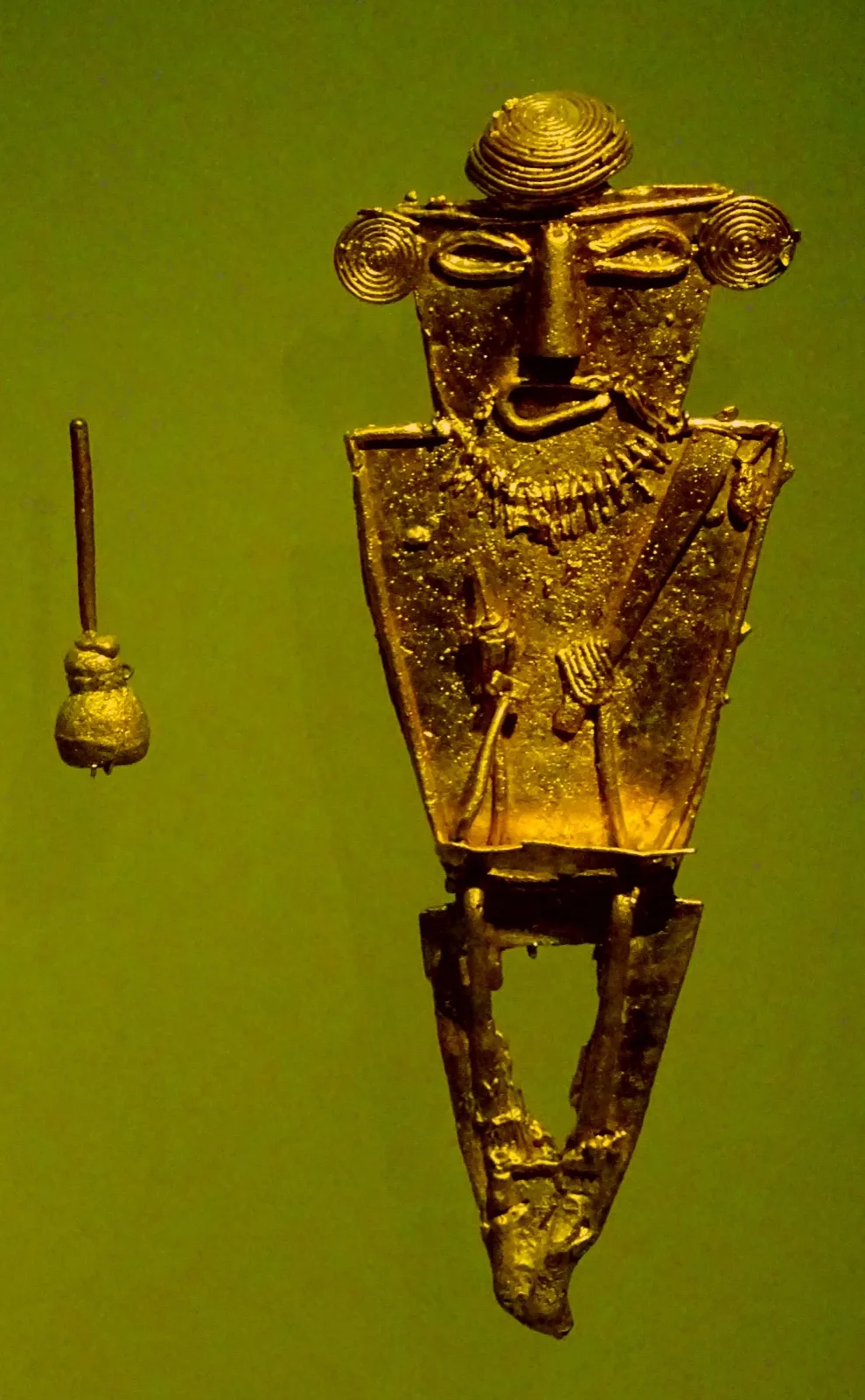 Tunjo muisca: figura votiva plana de oro con rostro frontal y aplicaciones de hilos, en el Museo del Oro de Bogotá.